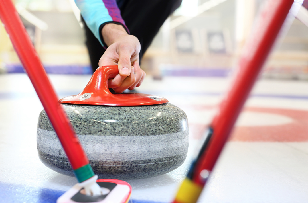 A curling stone and two sweepers